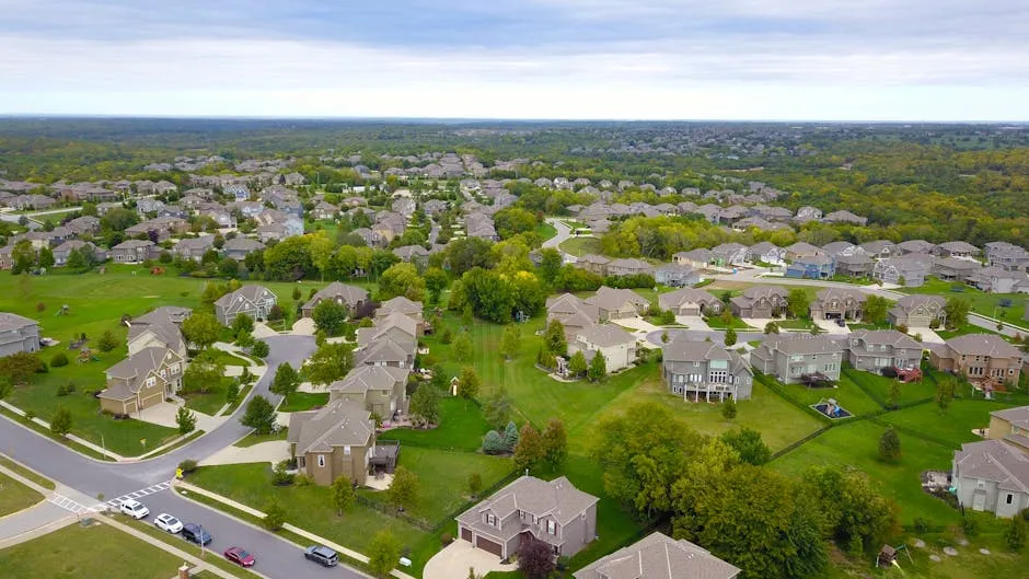 Aerial view of a suburban neighborhood with houses, roads, and lush greenery.