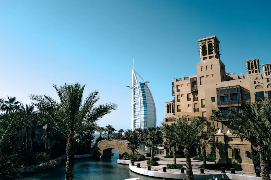 Beautiful daytime view of Burj Al Arab with palm trees and Jumeirah architecture.