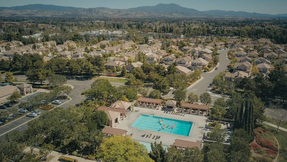 Aerial shot of a suburban neighborhood featuring a community swimming pool on a sunny day.