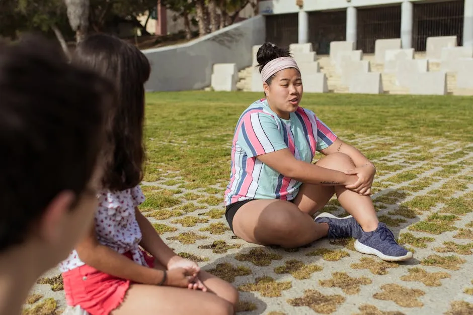 Children enjoying outdoor activities at a summer camp, sitting on grass and chatting.