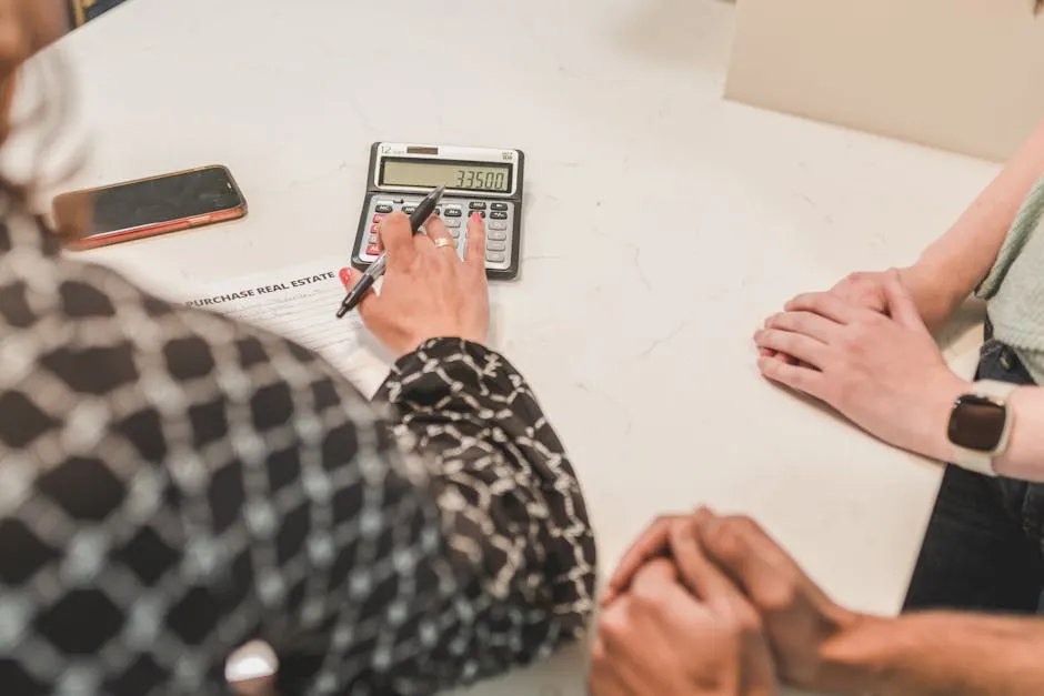 Close-up of hands during a real estate transaction with a calculator and purchase document on the table.