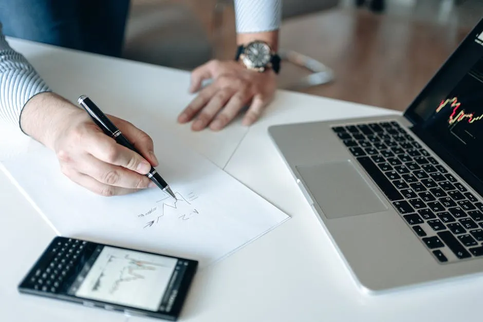 A professional analyzing financial graphs on paper and a laptop, showcasing business strategy.